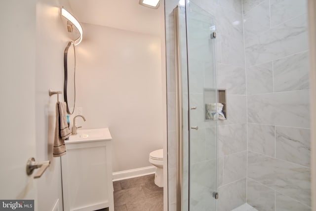 bathroom with a shower stall, vanity, toilet, and baseboards