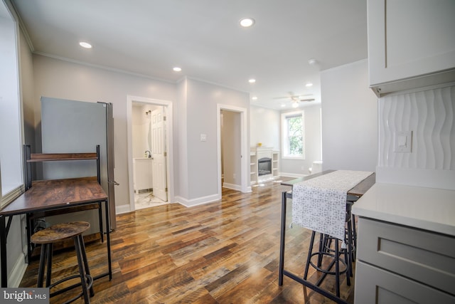 kitchen featuring ornamental molding, wood finished floors, recessed lighting, baseboards, and freestanding refrigerator