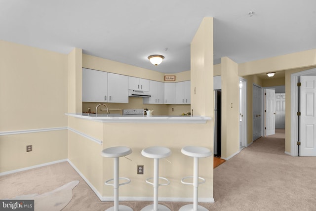 7617 Stony Creek Ln, Ellicott City, MD 21043 - kitchen with under cabinet range hood, light colored carpet, freestanding refrigerator, and a peninsula