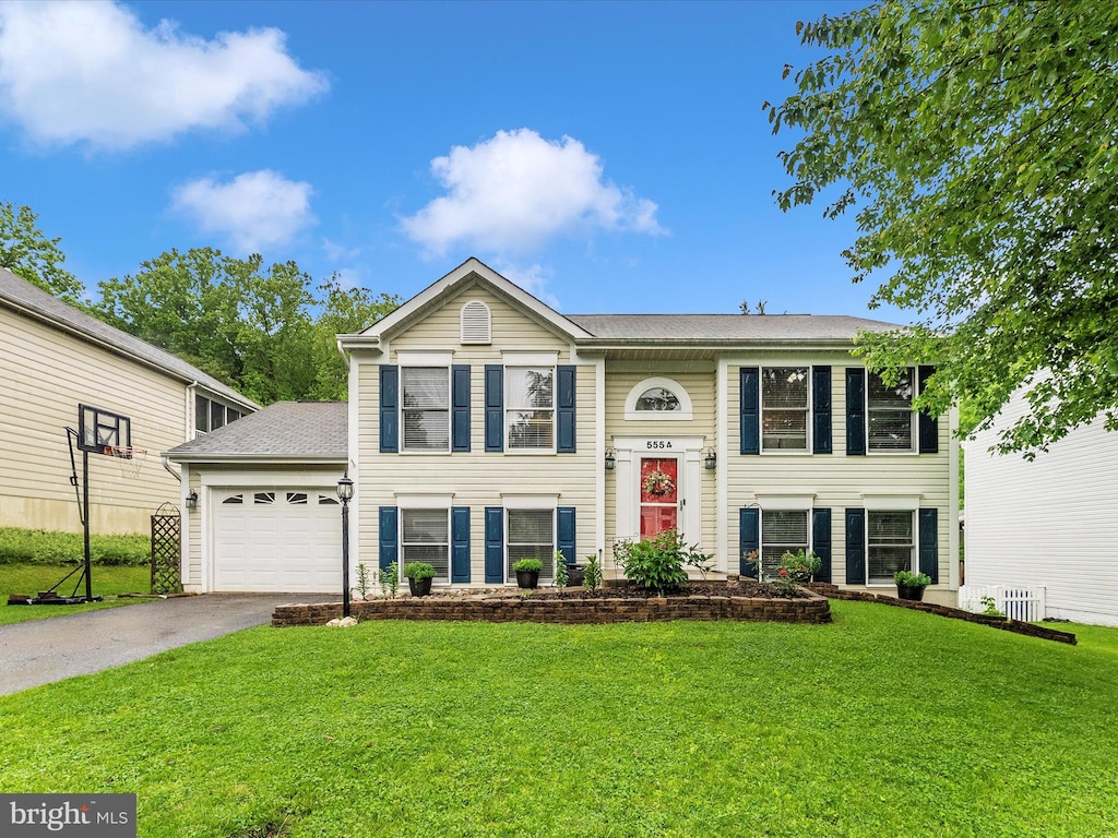 bi-level home with a garage, a front yard, and asphalt driveway