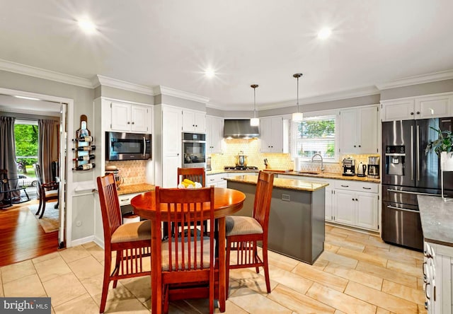 94 N Woodland Ave, Woodbury, NJ 08096 - kitchen featuring appliances with stainless steel finishes, range hood, a center island, tasteful backsplash, and healthy amount of natural light