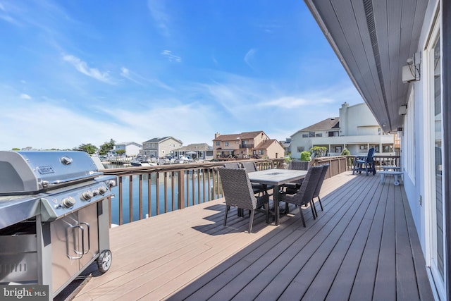 wooden deck with outdoor dining area, a residential view, a water view, and grilling area
