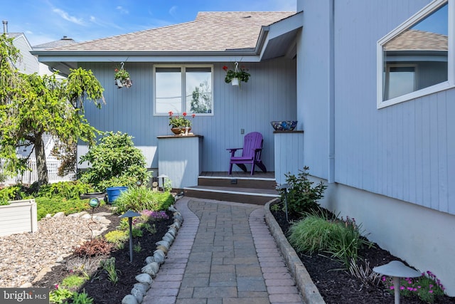 doorway to property with roof with shingles