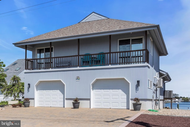 coastal home featuring a shingled roof, a garage, driveway, and cooling unit