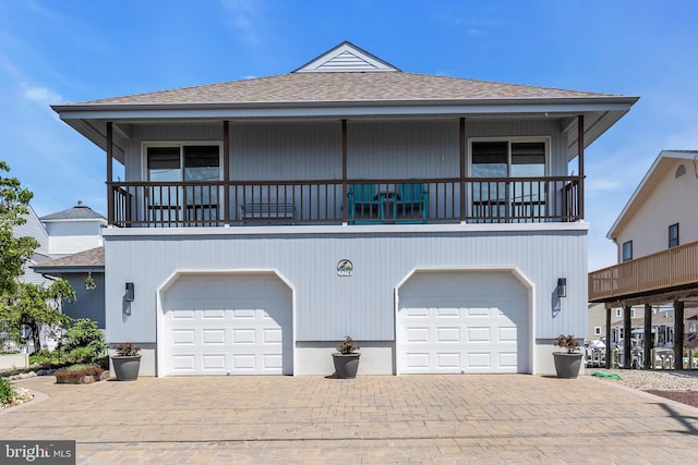 coastal home featuring a shingled roof, decorative driveway, and a garage