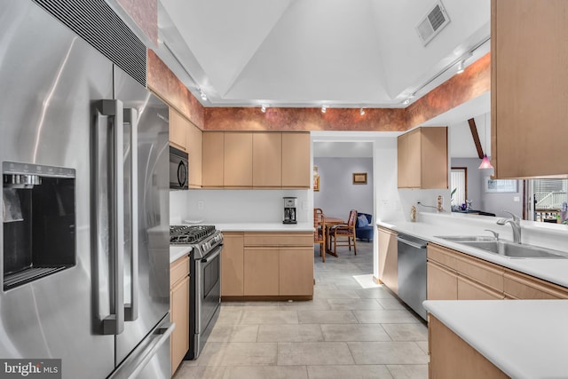 kitchen featuring stainless steel appliances, a sink, lofted ceiling, light countertops, and light brown cabinets