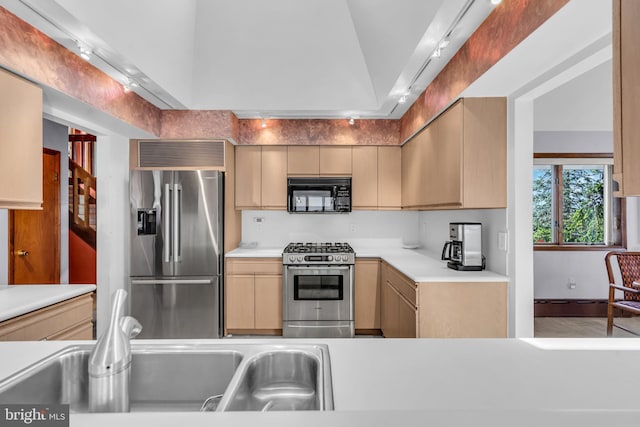 kitchen featuring appliances with stainless steel finishes, light brown cabinets, a sink, light countertops, and lofted ceiling
