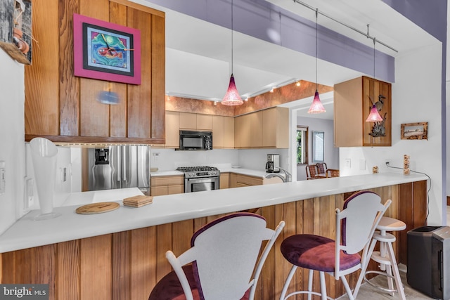 kitchen featuring appliances with stainless steel finishes, a peninsula, light countertops, and pendant lighting