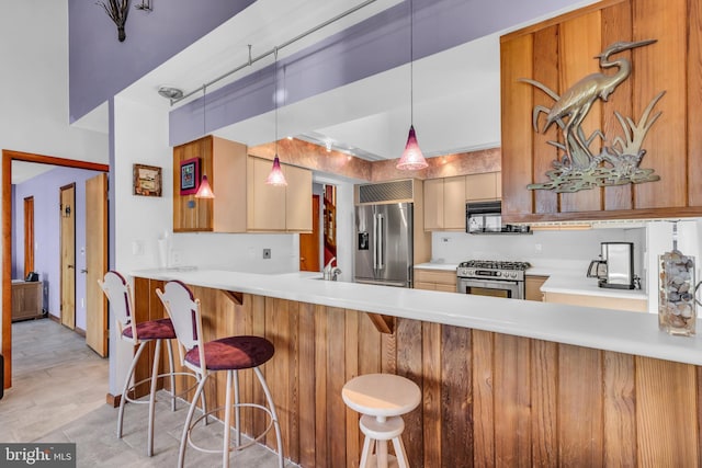 kitchen featuring stainless steel appliances, light countertops, a peninsula, and decorative light fixtures