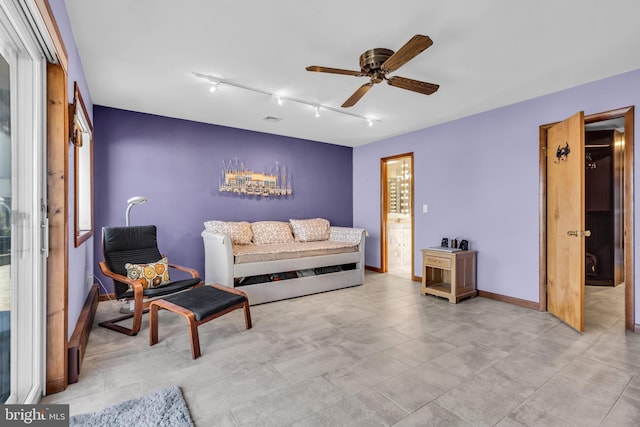 living area with a ceiling fan, rail lighting, and baseboards