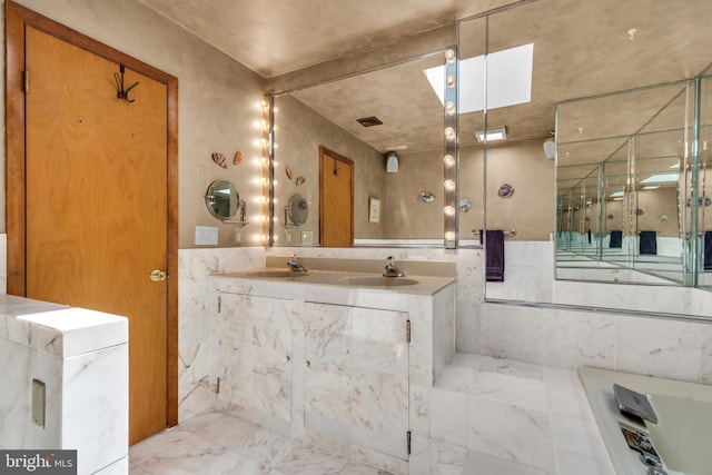 full bath featuring marble finish floors, vanity, and tile walls
