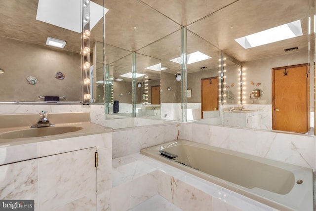 full bath with a skylight, a garden tub, and vanity