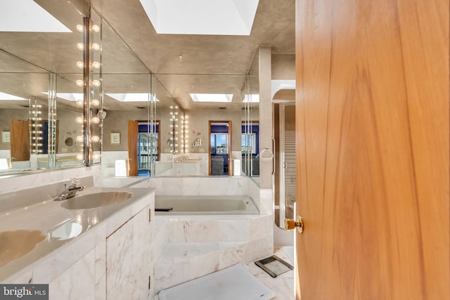 full bathroom with a skylight, vanity, and a garden tub