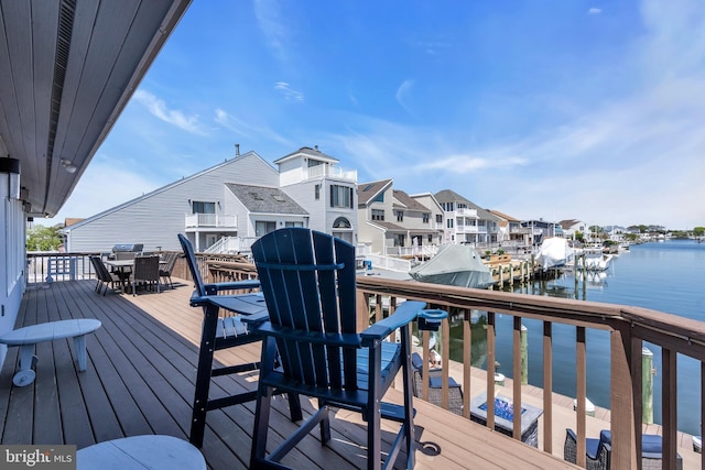 wooden terrace with a water view, outdoor dining area, and a residential view