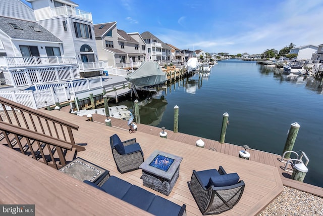 dock with an outdoor fire pit, a water view, and a residential view