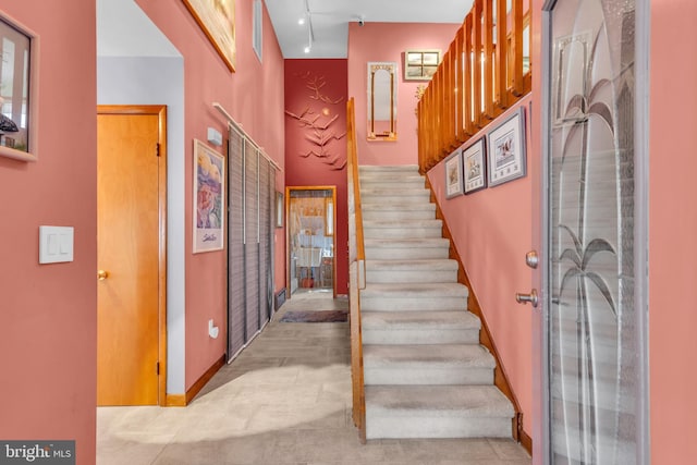 staircase featuring baseboards and track lighting