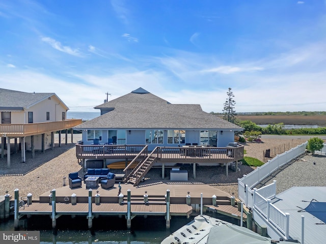 back of property featuring a deck with water view, roof with shingles, and an outdoor living space
