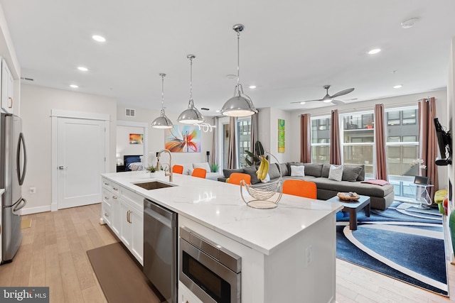 23650 Havelock Walk Ter Unit 303, Ashburn, VA 20148 - kitchen featuring a sink, stainless steel appliances, an island with sink, white cabinetry, and light wood-style floors