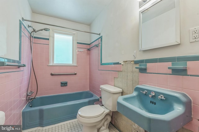 full bathroom featuring tile walls, tile patterned floors, a sink, toilet, and shower / washtub combination