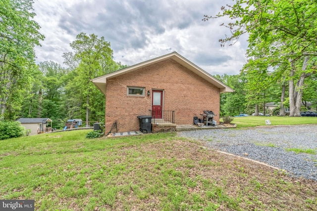 back of house with brick siding, a lawn, and central air condition unit