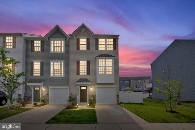 townhome / multi-family property featuring concrete driveway, a front lawn, and an attached garage