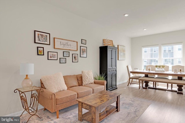 living area with baseboards, light wood-type flooring, and recessed lighting