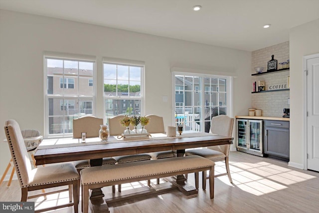 dining area with beverage cooler, a dry bar, light wood finished floors, and recessed lighting