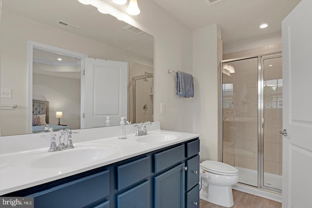 ensuite bathroom featuring a stall shower, double vanity, toilet, wood finished floors, and recessed lighting