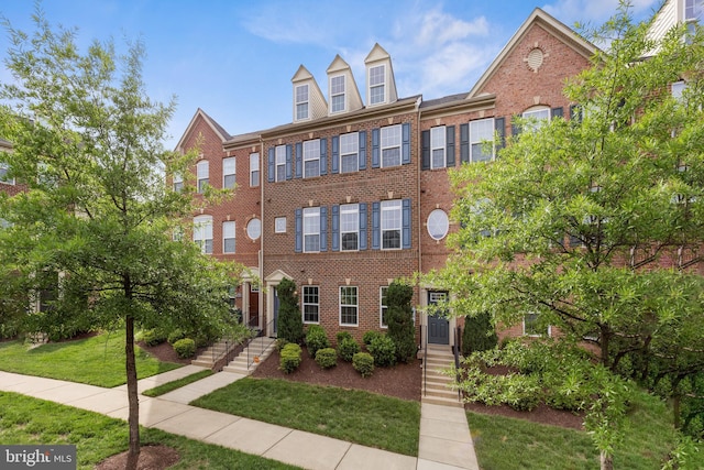 multi unit property featuring brick siding and a front yard