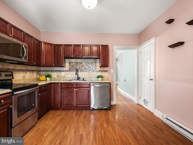 556 W Walnut St, Pottstown, PA 19464 - kitchen featuring stainless steel appliances, a sink, a baseboard heating unit, light wood-type flooring, and backsplash