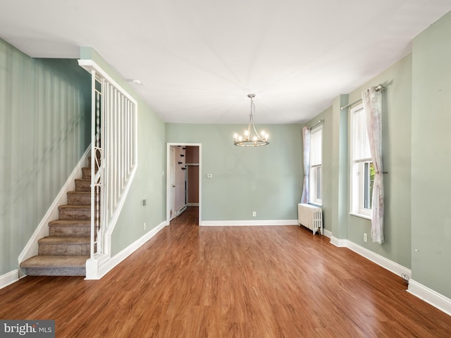 556 W Walnut St, Pottstown, PA 19464 - empty room with radiator heating unit, wood finished floors, a chandelier, stairs, and baseboards