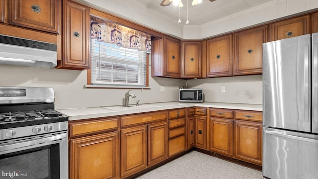 kitchen featuring stainless steel appliances, brown cabinets, a sink, light countertops, and crown molding