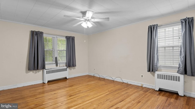 unfurnished room featuring radiator heating unit, light wood finished floors, a ceiling fan, baseboards, and crown molding