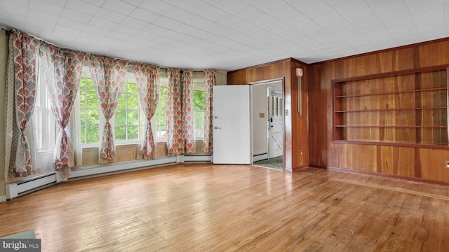 unfurnished living room featuring wood walls, hardwood / wood-style floors, and a baseboard radiator