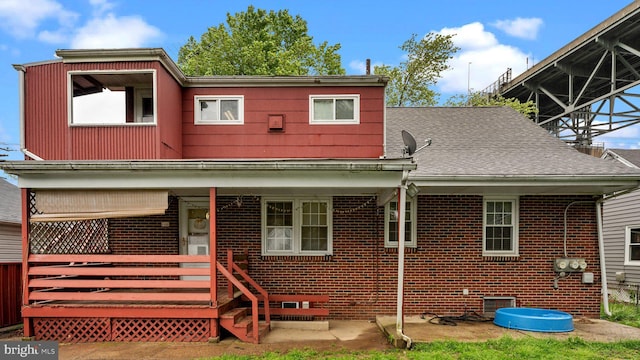 rear view of house featuring brick siding and a shingled roof