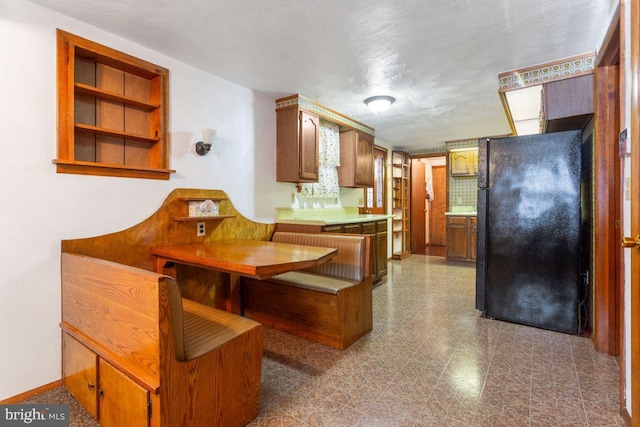 449 Carlisle St, Hanover, PA 17331 - kitchen with freestanding refrigerator, brown cabinetry, light countertops, dark flooring, and baseboards
