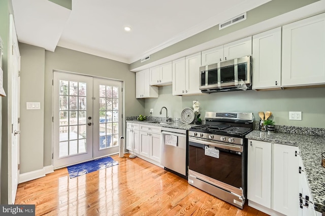 kitchen featuring stainless steel appliances, a sink, french doors, white cabinets, and light wood-style flooring