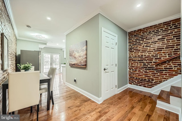 hallway featuring brick wall, wood finished floors, baseboards, crown molding, and recessed lighting