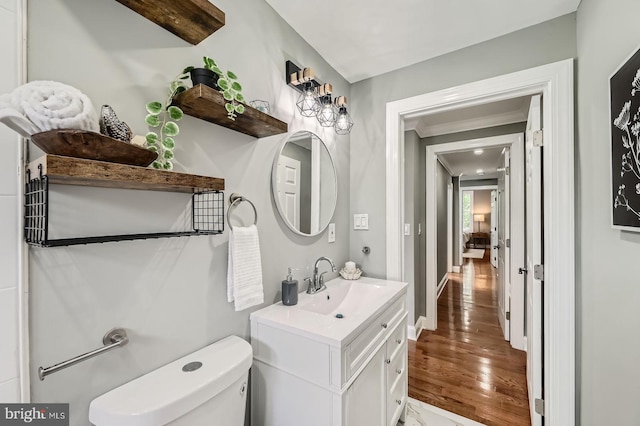 half bath with wood finished floors, vanity, toilet, and baseboards