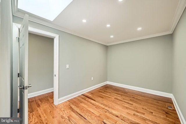 empty room featuring crown molding, recessed lighting, baseboards, light wood-type flooring, and a skylight