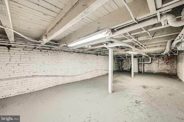 unfinished below grade area with water heater and brick wall