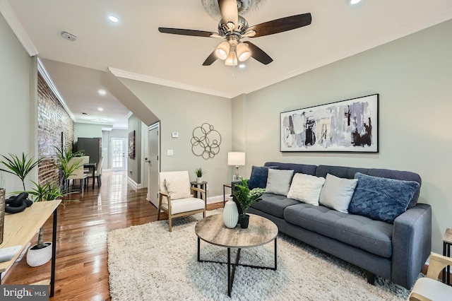 living room featuring wood finished floors, ceiling fan, crown molding, baseboards, and recessed lighting