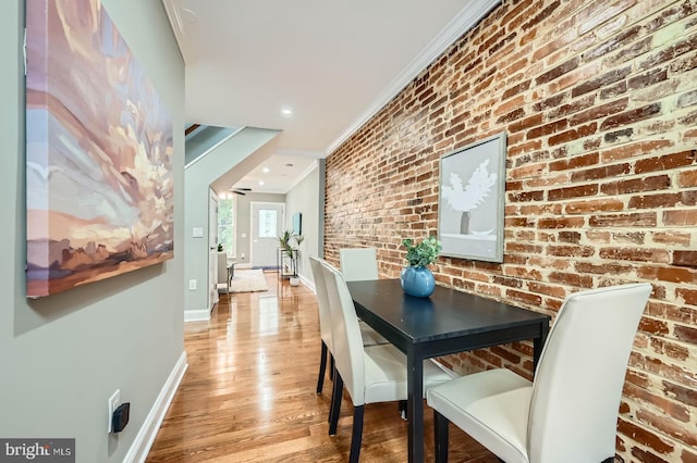 dining space featuring ornamental molding, baseboards, light wood-type flooring, brick wall, and recessed lighting