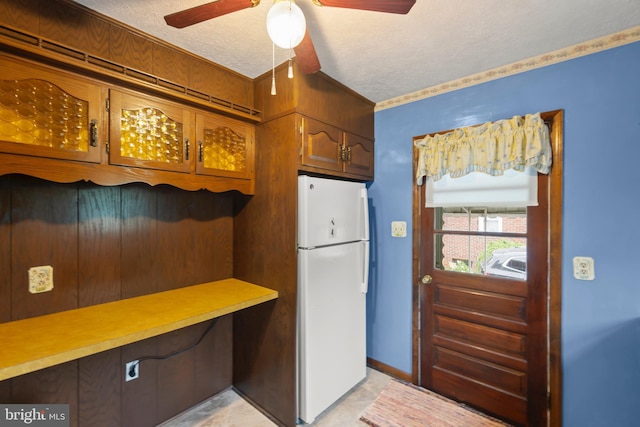 kitchen with freestanding refrigerator, a textured ceiling, a ceiling fan, light countertops, and brown cabinets