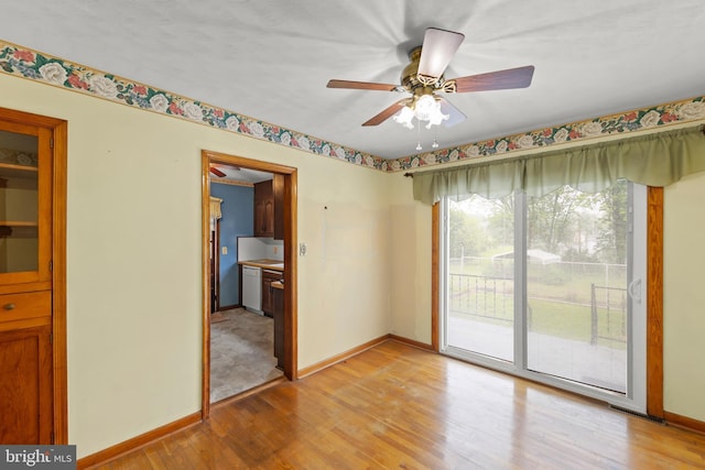 spare room with baseboards, light wood-style floors, and ceiling fan