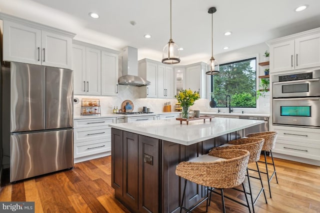 42004 Donnington Pl, Ashburn, VA 20148 - kitchen with stainless steel appliances, wall chimney range hood, a sink, light countertops, and recessed lighting