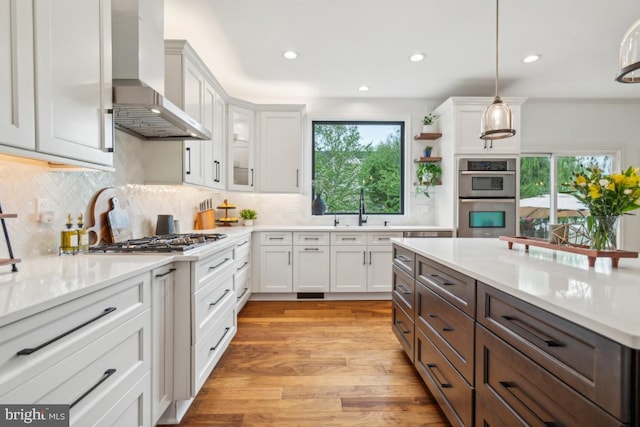 42004 Donnington Pl, Ashburn, VA 20148 - kitchen featuring wall chimney range hood, stainless steel appliances, white cabinets, light countertops, and light wood-style flooring