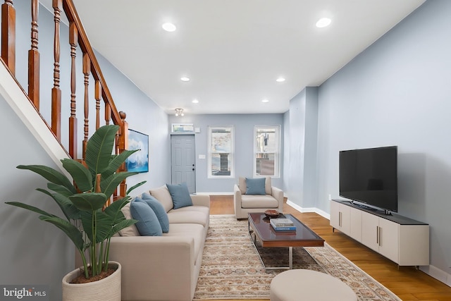 living area featuring light wood-style flooring, recessed lighting, baseboards, and stairway