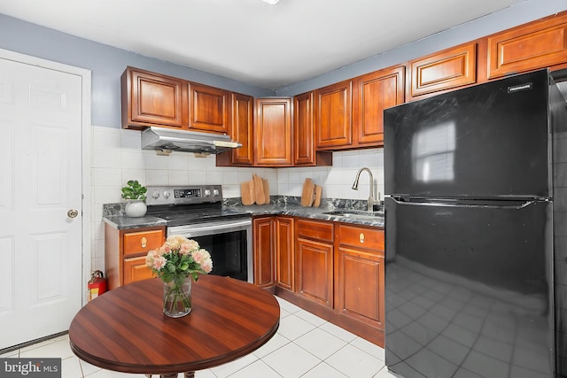 kitchen with freestanding refrigerator, stainless steel electric stove, a sink, under cabinet range hood, and light tile patterned floors