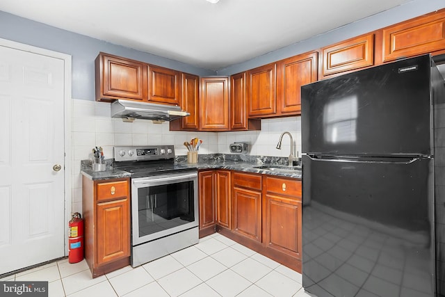 kitchen with freestanding refrigerator, stainless steel range with electric cooktop, a sink, under cabinet range hood, and light tile patterned floors